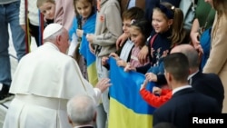 Pope Francis greets children holding up a Ukrainian flag during the weekly general audience at the Vatican, Feb. 22, 2023.