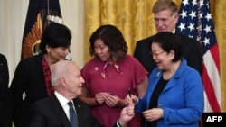 President Joe Biden hands a pen to Sen. Mazie Hirono, D-Hawaii, after signing the COVID-19 Hate Crimes Act, in the East Room of the White House in Washington, May 20, 2021. 