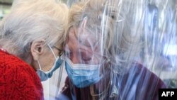 FILE - A resident, left, of the Domenico Sartor nursing home in Castelfranco Veneto, near Venice, Italy, hugs her visiting daughter Nov. 11, 2020, through a plastic screen in a so-called 'Hug Room' amid the new coronavirus pandemic.