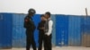 FILE - A police officer talks to men in a street in Kashgar, Xinjiang Uighur Autonomous Region, China, March 24, 2017. 