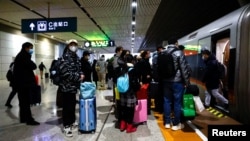 People wait with luggage to board a train at a railway station, amid the COVID-19 outbreak, in Wuhan, Hubei province, China Jan. 1, 2023. 