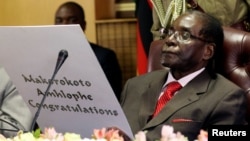 Former Zimbabwe's President Robert Mugabe reads a card during his 93rd birthday celebrations in Harare, Feb. 21, 2017. 