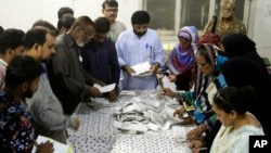 Pakistani election staff count the votes after polls closed at a polling station for the parliamentary elections in Karachi, Pakistan, July 25, 2018.