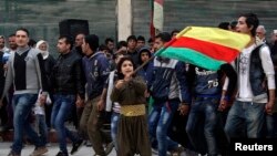 A Kurdish boy waves a Kurdish flag during celebrations after it was reported that Kurdish forces took control of the Syrian town of Kobani, in Sheikh Maksoud neighborhood of Aleppo, Jan. 27, 2015.