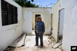 Tinsmith Otoniel Ramos Aponte poses for a portrait, May 16, 2018, inside his mother's home, which lost its roof to Hurricane Maria but did not qualify for federal aid for repair in Yabucoa, a town where many continue without power in Puerto Rico.