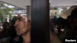 FILE - An ethnic Hazara man looks out from behind a glass panel at a temporary shelter in Karawang, Indonesia's West Java province.
