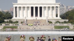 FILE - Soldiers dressed in WWII uniforms place wreaths in front of the Freedom Wall, with the Lincoln Memorial in the background, at the World War II Memorial in Washington, May 8, 2015.