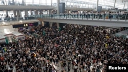 Protesters surround banners that read "Those charge to the street on today is brave!," center top, and "Release all the detainees!" during a sit-in rally at the arrival hall of the Hong Kong International airport in Hong Kong, Monday, Aug. 12, 2019. 