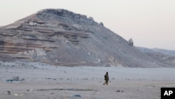 FILE - In this photo taken March 6, 2017, a Somali government soldier walks on the beach in Eyl, in Somalia's semiautonomous northeastern state of Puntland. Somali pirates have seized a small boat, kidnapped its Indian crew members, and are taking the ves