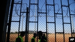 Guards walk past a razor wire fence securing a former prison in Drahonice, Czech Republic, Friday, Oct. 2, 2015. Anticipating a possible influx of migrants in the country, the Czech Republic is turning the prison into a new detention center for up to 240 of them.