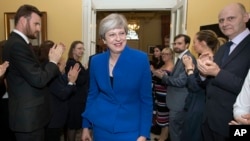 Britain's Prime Minister Theresa May is applauded by staff as she returns to 10 Downing Street, after seeking permission from Queen Elizabeth to form a new government, in London, June 9, 2017. 
