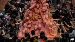 Mahasiswa membersihkan patung "Pilar Malu", peringatan bagi mereka yang tewas dalam penumpasan Tiananmen 1989, di Universitas Hong Kong, Jumat, 4 Juni 2021. (AP Photo/Kin Cheung)
