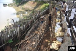 Indian laborers work to build up a river bank after floodwaters and incessant rain eroded away the edges of the River Brahmaputra in Guwahati, June 15, 2017.