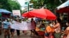 Anti-coup protesters hold signs that read 'We Support NUG,' which stands for ‘National Unity Government,’ as they march on a street where vendors sell fresh products April 17, 2021, in Yangon, Myanmar. 