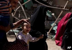 A girl with a shaved head and her father cry as the family flees the al-Rifai neighborhood while Iraqi special forces battle Islamic State militants in western Mosul, Iraq, May 17, 2017.