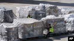FILE - An air cargo employee checks pallets of imported items, at Miami International Airport in Miami, Feb. 7, 2025. Some experts say new tariffs on imported goods are partly to blame for February's drop in consumer confidence.