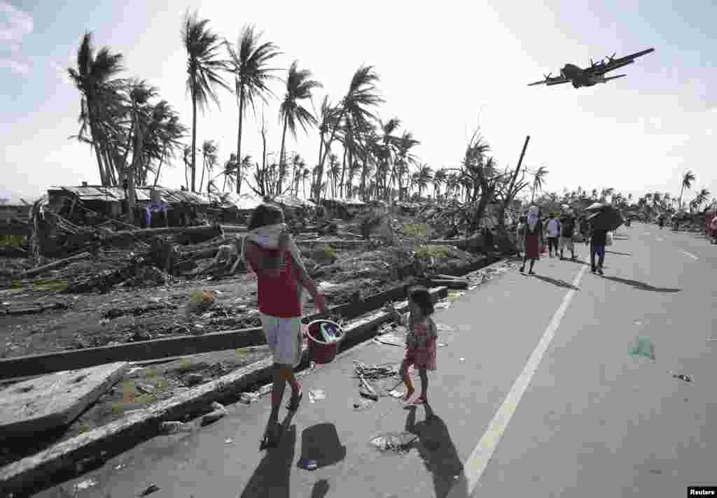 Survivors look up at a military C-130 plane as it arrives at typhoon-ravaged Tacloban city, Leyte province, central Philippines, Nov. 11, 2013.&nbsp;