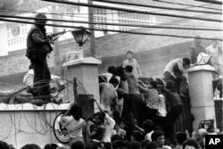 FILE - Mobs of Vietnamese people scale the wall of the U.S. Embassy in Saigon, Vietnam, trying to get to the helicopter pickup zone, just before the end of the Vietnam War, April 29, 1975.