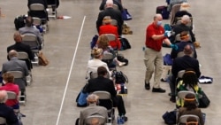 A worker cleans a microphone after a question by a member of the N.H. House of Representatives during a legislative session on the drained ice hockey rink at the University of New Hampshire in Durham, New Hampshire, June 30, 2020.