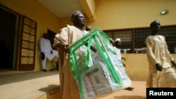 An electoral staff member carries electoral materials outside the Independent National Electoral Commission (INEC) office in Daura, Katsina State, Nigeria, Feb. 22, 2019.
