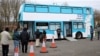 People queue outside a bus modified into a mobile vaccination center for the coronavirus disease (COVID-19), in London, on February 14, 2021.
