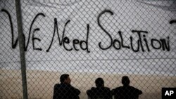 Migrants assis sous une devant un stade olympique a Faliro au sud d'Athenes, le 15 decembre 2015.