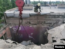 یک امداد‌گر بالای بام یک ساختمان مسکونی در نیکوپول که بر اثر حمله راکتی روسیه فروریخته است - ۱۶ ژوئیه ۲۰۲۲