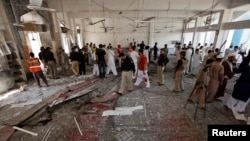 Security officials, rescue workers and members of the media gather at the site of a suicide bomb attack in Shi'ite Muslim mosque in Peshawar, Pakistan, June 21, 2013. 