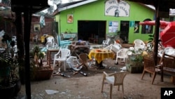 FILE - Damaged chairs and tables lie among the debris strewn after a bomb attack outside an Ethiopian restaurant in Kampala, Uganda, July 12, 2010.