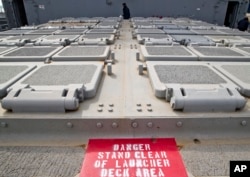 FILE - A U.S. Marine serviceman walks by missile launch pads on the deck of the USS Vicksburg in the Black Sea port of Constanta, Romania.