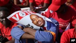 FILE - An opposition party supporter covers his face with a campaign poster of Nelson Chamisa in Harare, July 28, 2018.