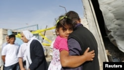 A man carrying a girl walks past by the damaged house where five Turkish civilians were killed by a mortar bomb in the southern border town of Akcakale, October 4, 2012.