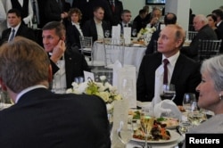 FILE - Russian President Vladimir Putin (R) sits next to retired U.S. Army Lieutenant General Michael Flynn (L) as they attend a banquet marking the 10th anniversary of RT (formerly Russia Today) television news channel in Moscow, Russia, Dec. 10, 2015.