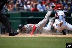 Boston Red Sox' Rafael Devers, left, slides home past Washington Nationals catcher Pedro Severino to score on a sacrifice fly by Jackie Bradley Jr., during the seventh inning of a baseball game Wednesday, July 4, 2018, in Washington.