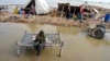 FILE - A woman, surrounded by floodwaters, sits near her belongings, in Sohbat Pur, Pakistan, Sep. 3, 2022. The flooding that year killed at least 1,700 people. The nation's weather officials reported on May 3, 2024, that Pakistan last month had its wettest April since 1961.