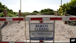 A sign is posted at a closed entrance to the beach July 3, 2020, in the South Beach neighborhood of Miami Beach, Fla. as beaches throughout South Florida are closed for the busy Fourth of July weekend to avoid further spread of the new coronavirus. 