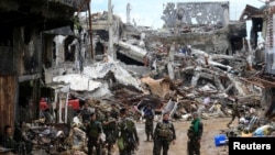 Government soldiers stand in front of damaged houses and buildings in Marawi city, Philippines, Oct. 25, 2017.