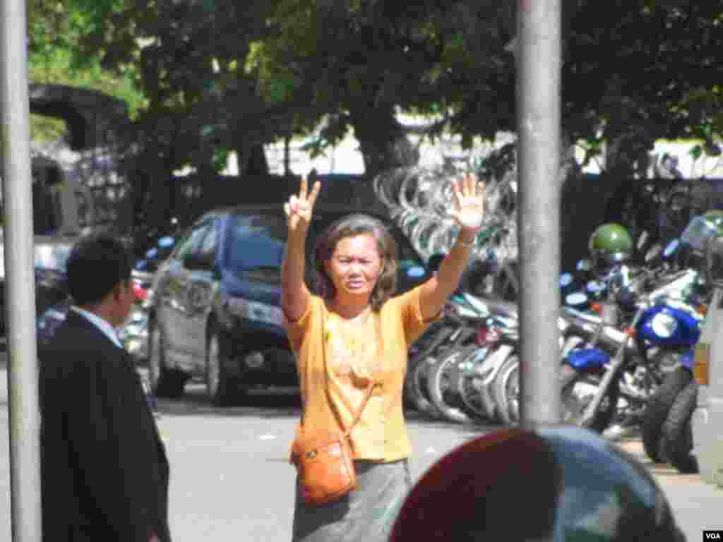 Mu Sochua raises her hands showing a seven-finger sign, representing her party, to supporters from inside a police compound, Phnom Penh, Cambodia, July 15, 2014. (Khoun Theara/VOA)