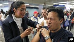 A man is vaccinated against 'swine flu' by a nurse in a subway station in Mexico City, Jan. 18, 2010