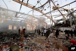 People inspect the aftermath of a Saudi-led coalition airstrike in Sanaa, Yemen, Oct. 8, 2016.