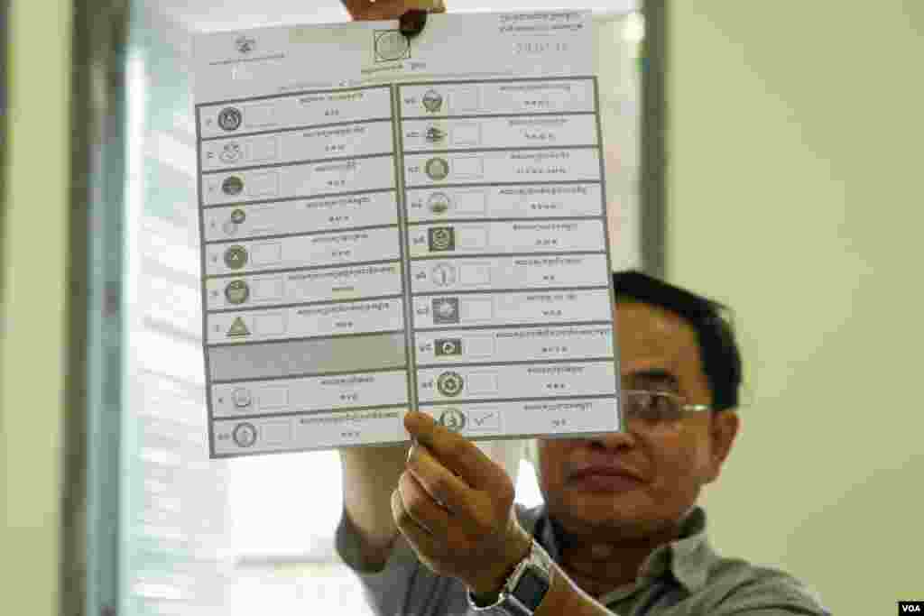 មន្ត្រីរៀបចំការបោះឆ្នោតលើកបង្ហាញសន្លឹកឆ្នោតមួយសន្លឹក​​ បន្ទាប់ពីការិយាល័យ​បោះឆ្នោតនៅទូទាំងប្រទេសបានបិទ នៅសង្កាត់បឹងកេង​កង២ ខណ្ឌ​ចំការមន រាជធានីភ្នំពេញ​ នៅ​ថ្ងៃអាទិត្យ​ ទី២៩ ខែកក្កដា​ ឆ្នាំ២០១៨។ (ខាន់ សុគុំមនោ/VOA)