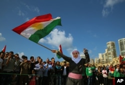 Syrian Kurd Nazdan, who fled her home in Qamishli, Syria, wears traditional clothes as she dances and waves a Kurdish flag, during a celebration of Nowruz day, in Beirut, Lebanon, Mar. 21, 2016.