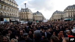 A crowd listens to musicians performing outside the Palais Garnier opera house, Jan. 18, 2020 in Paris.