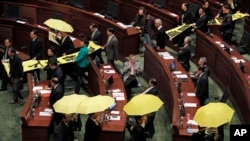 Anggota parlemen pro-demokrasi Hong Kong mengangkat payung kuning mereka dan melakukan aksi 'walk out' dari pidato kebijakan tahunan pimpinan Hong Kong, Leung Chun-ying (14/1). 
