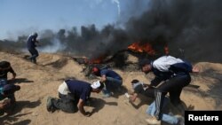 Palestinian demonstrators take cover from Israeli gunfire during a protest marking Jerusalem Day at the Israel-Gaza border in the southern Gaza Strip, June 8, 2018.