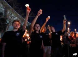 Attendees raise their candles at a candlelight vigil for the victims of the shooting at Marjory Stoneman Douglas High School, Feb. 15, 2018, in Parkland, Fla.