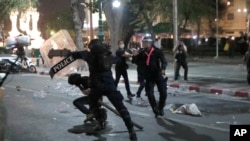 A riot policeman advances towards a man kneeling on the road during a protest in front of the Grand Palace, March 20, 2021 in Bangkok, Thailand. 