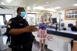 A parent and a member of the 'Community Patriots' confronts a police officer while protesting against wearing masks in schools, at the Administration Building in Largo, Florida, Aug. 9, 2021.