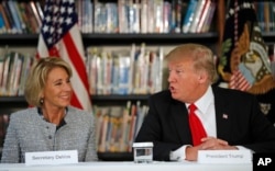 Education Secretary Betsy DeVos listens as President Donald Trump speaks during a round table discussion at Saint Andrew Catholic School, March 3, 2017, in Orlando, Florida.