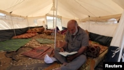 A Palestinian man reads the Koran inside a tent during the holy month of Ramadan, at a protest camp near the Israel-Gaza border in the central Gaza Strip, May 17, 2018. 